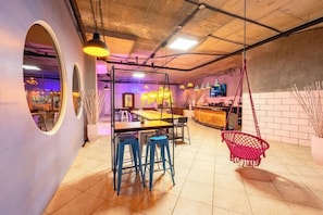 A modern interior with a bar area, seating, and a hanging chair.