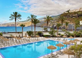 Una piscina al aire libre, sombrillas, sillones reclinables de piscina