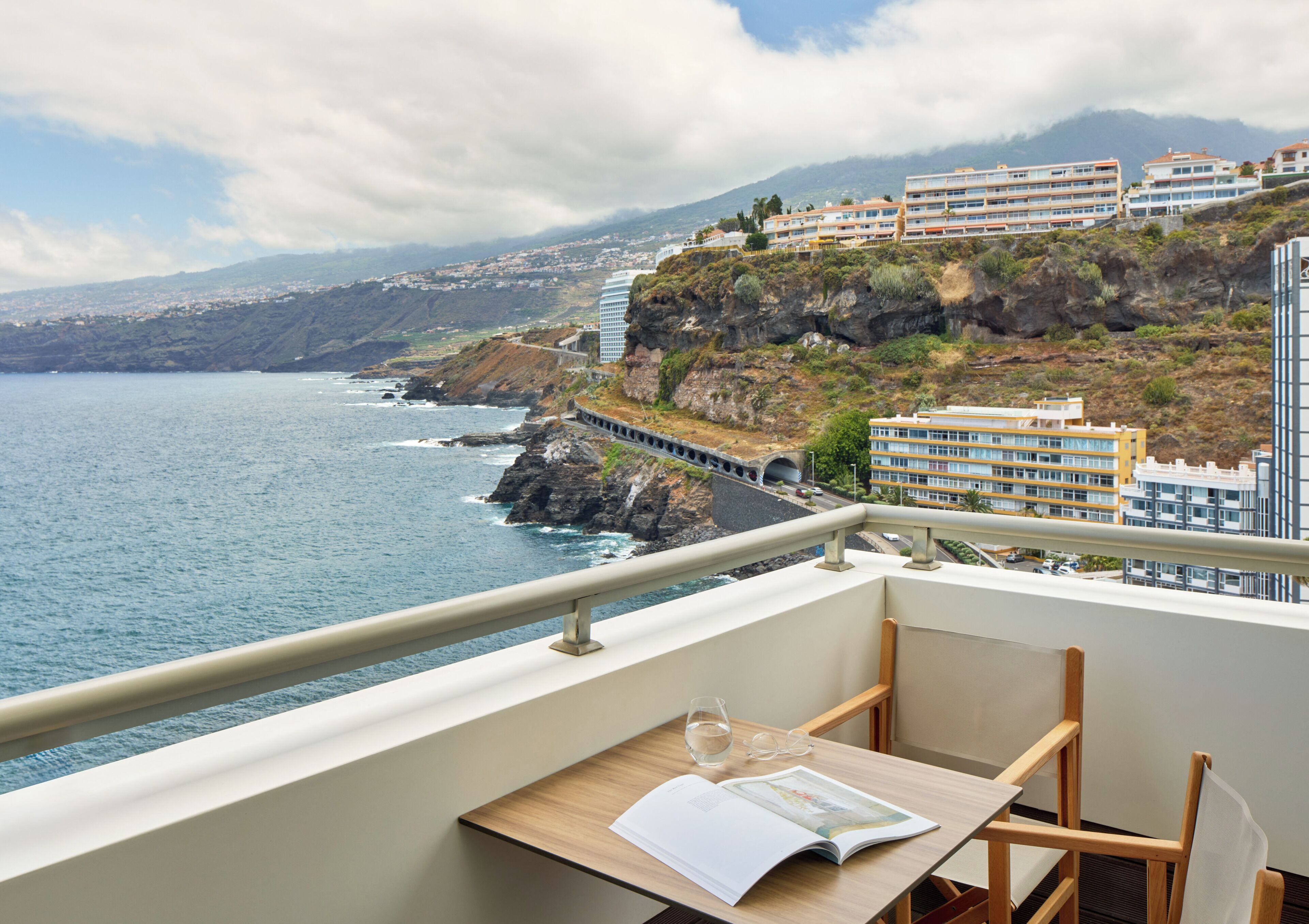 Un balcon avec une table, une paire de lunettes et un magazine ouvert.