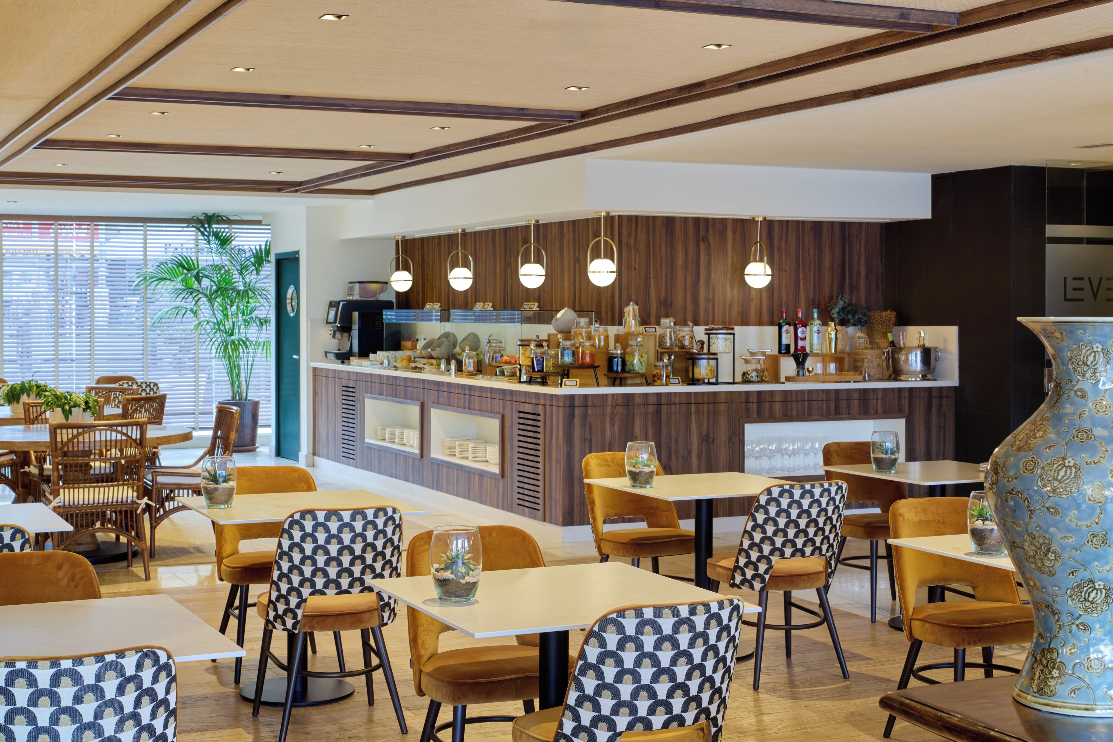 A modern restaurant with wooden accents, a bar area, and a large decorative vase.