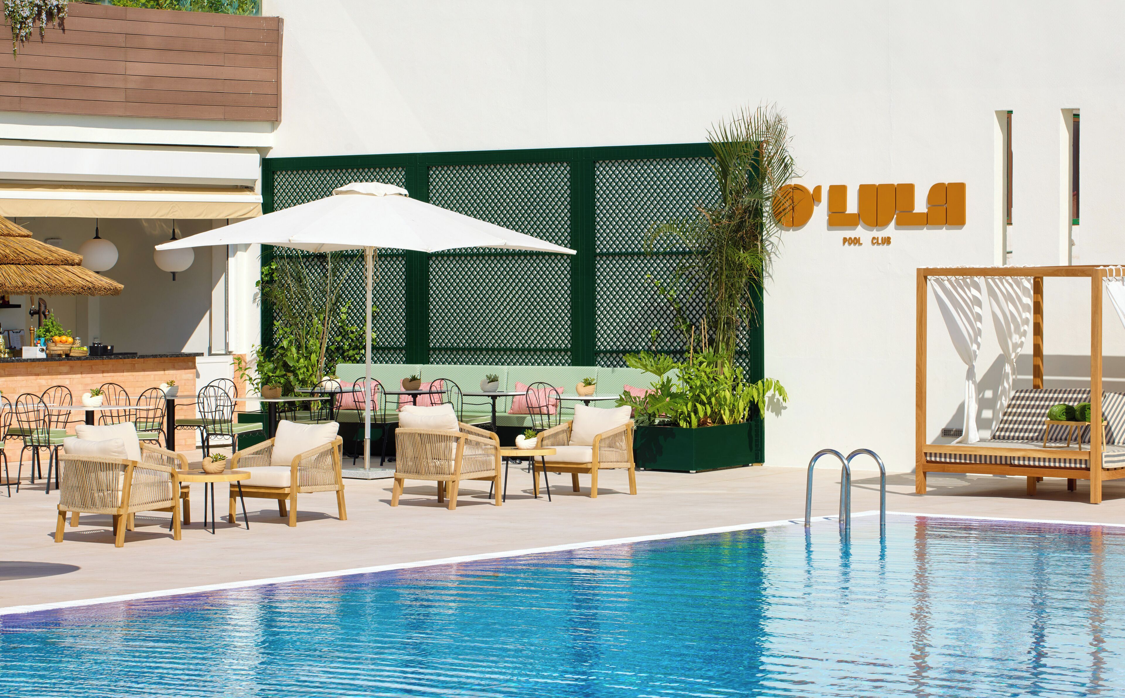 A pool area with lounge chairs and umbrellas, a bar, and a sign for 'LULA POOL CLUB'.