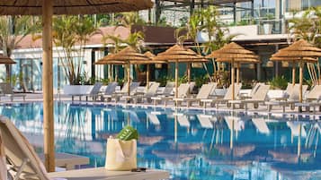 Una piscina al aire libre, sombrillas, sillones reclinables de piscina