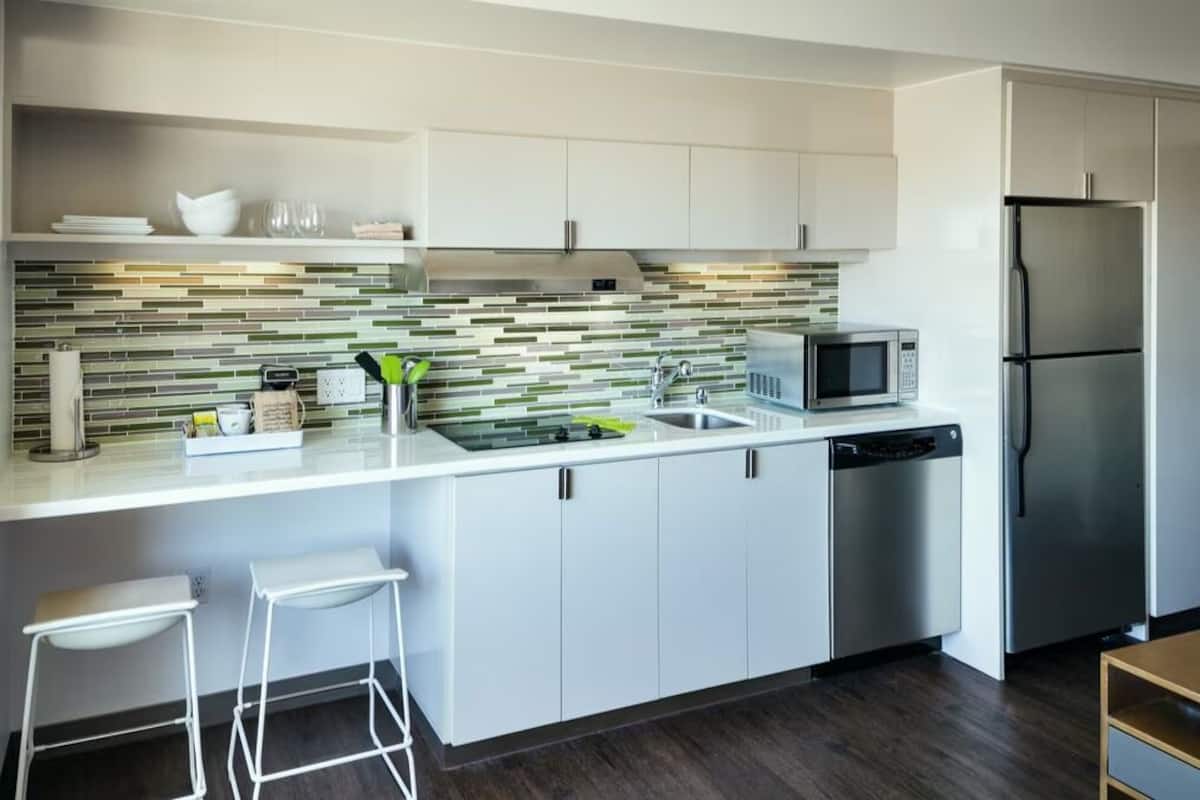 A modern kitchen with white cabinetry, a stainless steel refrigerator, a microwave, and a dishwasher.
