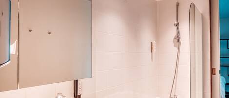 A modern bathroom with two sinks, a large mirror, and a walk-in shower.