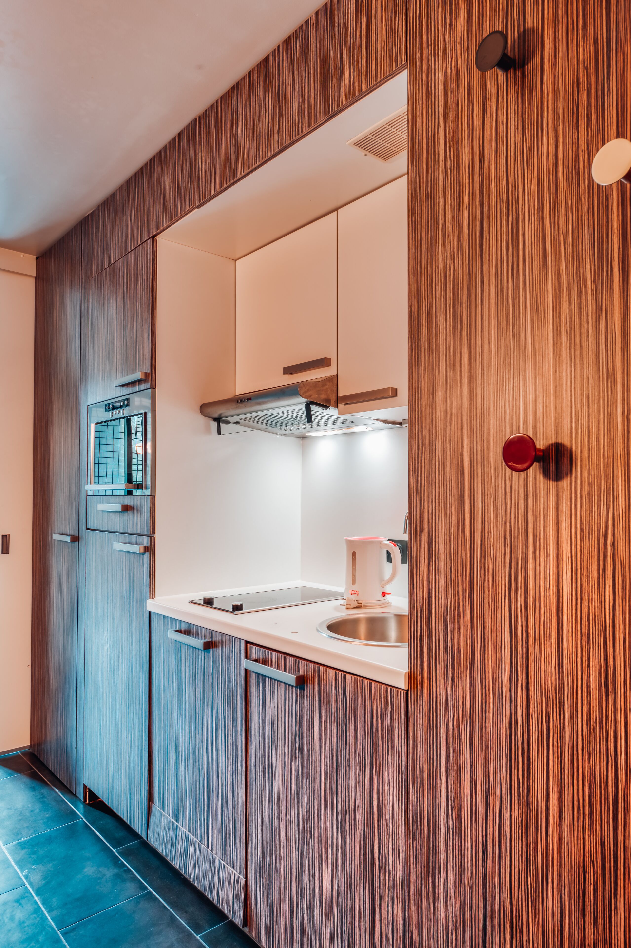 A modern kitchen with wooden cabinetry, a built-in oven, and a stainless steel sink.
