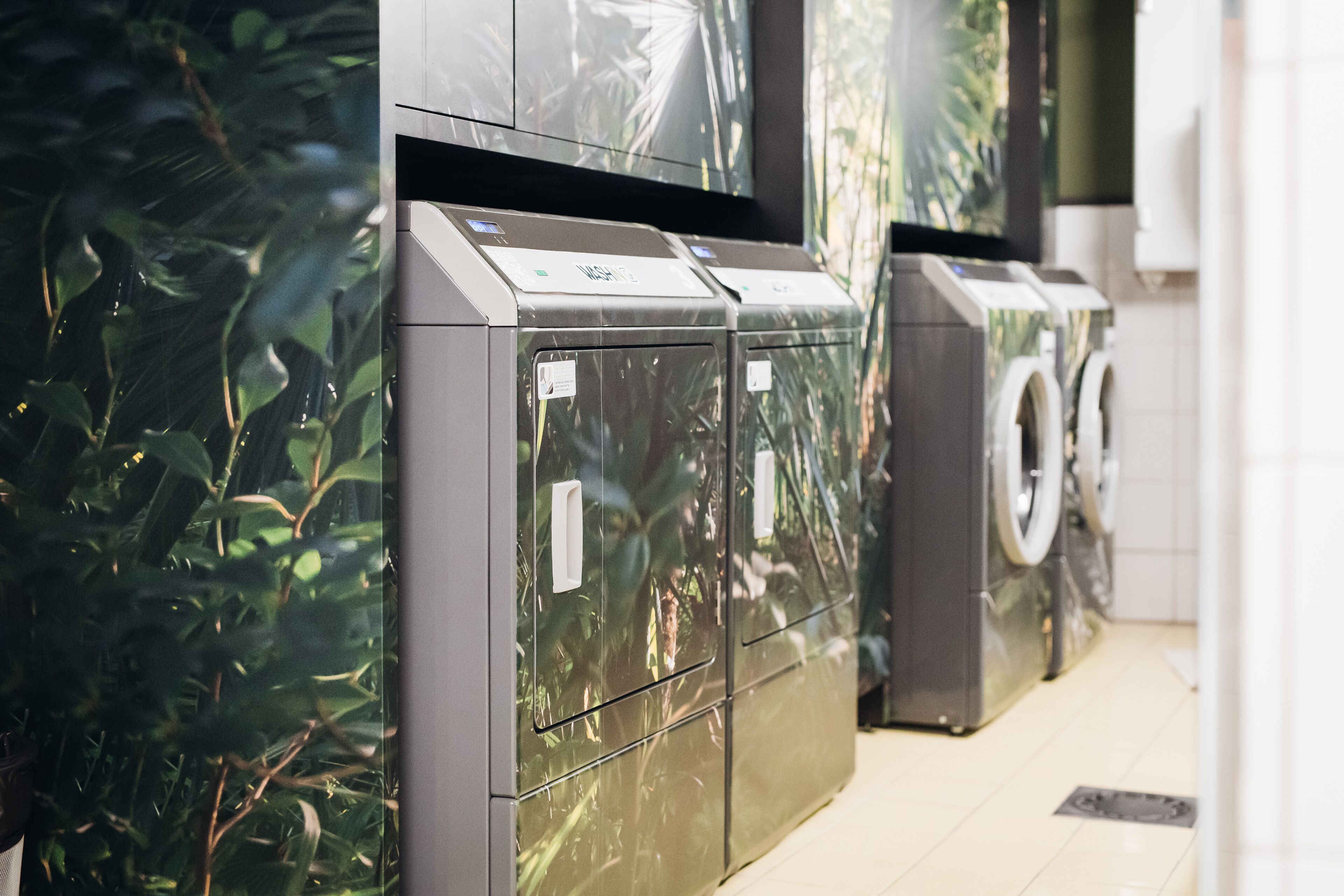 A row of modern, compact washing machines in a commercial setting.