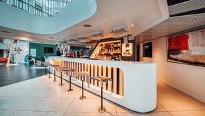Un espace bar moderne doté d’un comptoir incurvé, de tabourets de bar et d’un plafond haut avec des lucarnes.