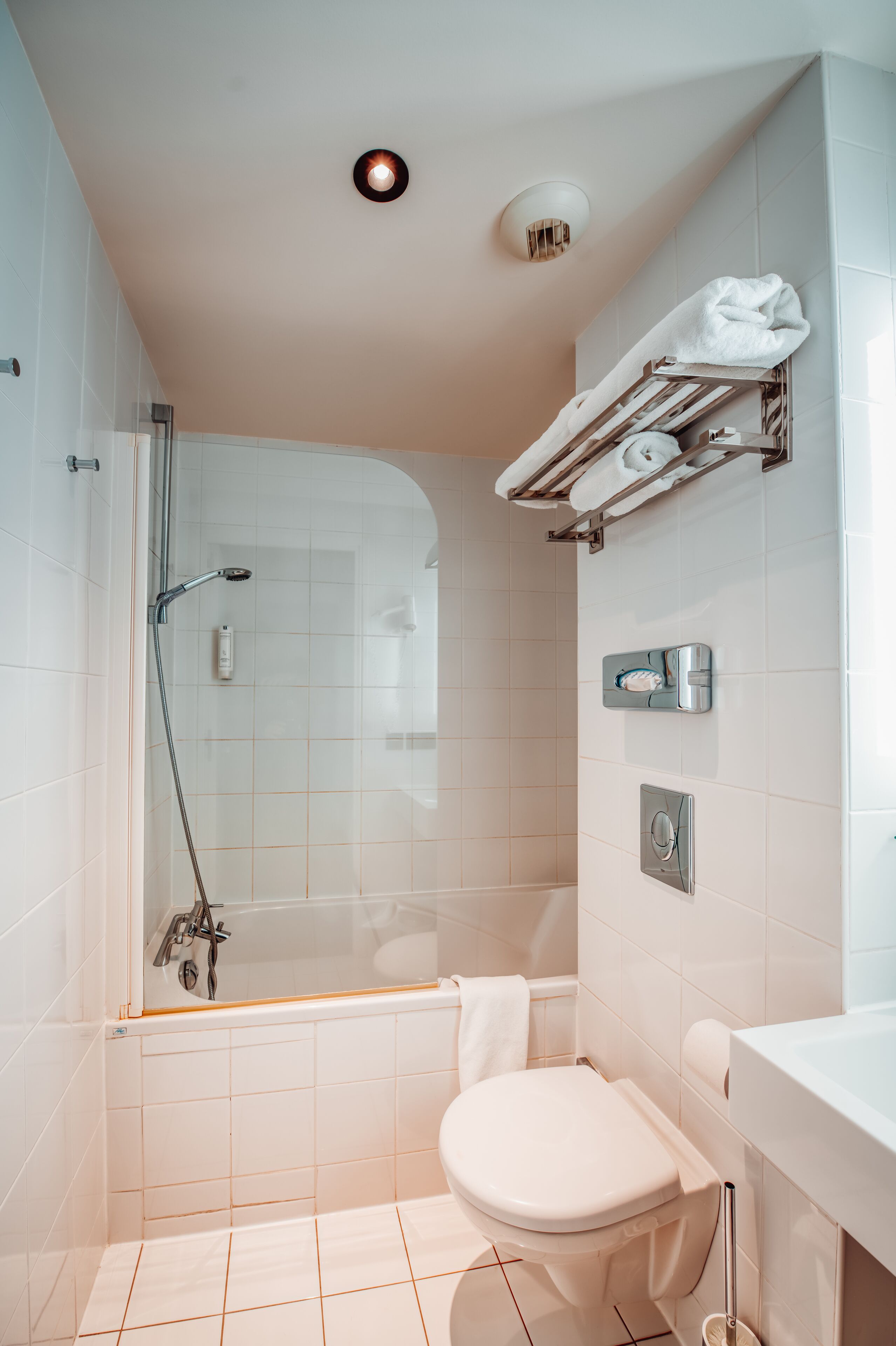A modern bathroom with a glass-enclosed shower, a white toilet, and a towel rack with towels.