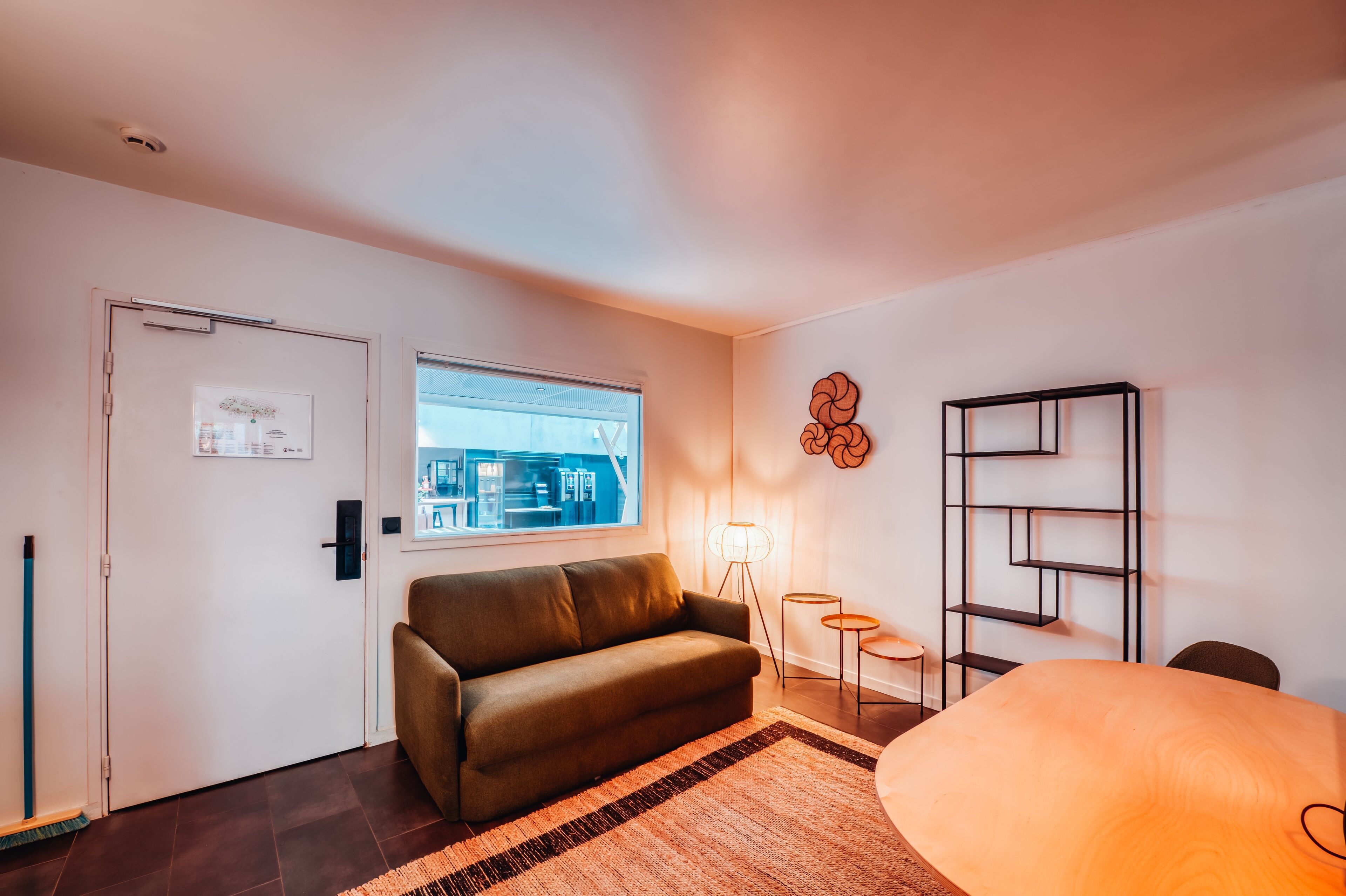 Una sala de estar moderna con un sofá, una mesa de centro, una lámpara de pie y una estantería.