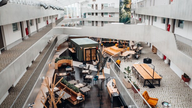 Un atrium à plusieurs niveaux, doté de différents espaces de détente, notamment des tables et des chaises, et d’un escalier central.
