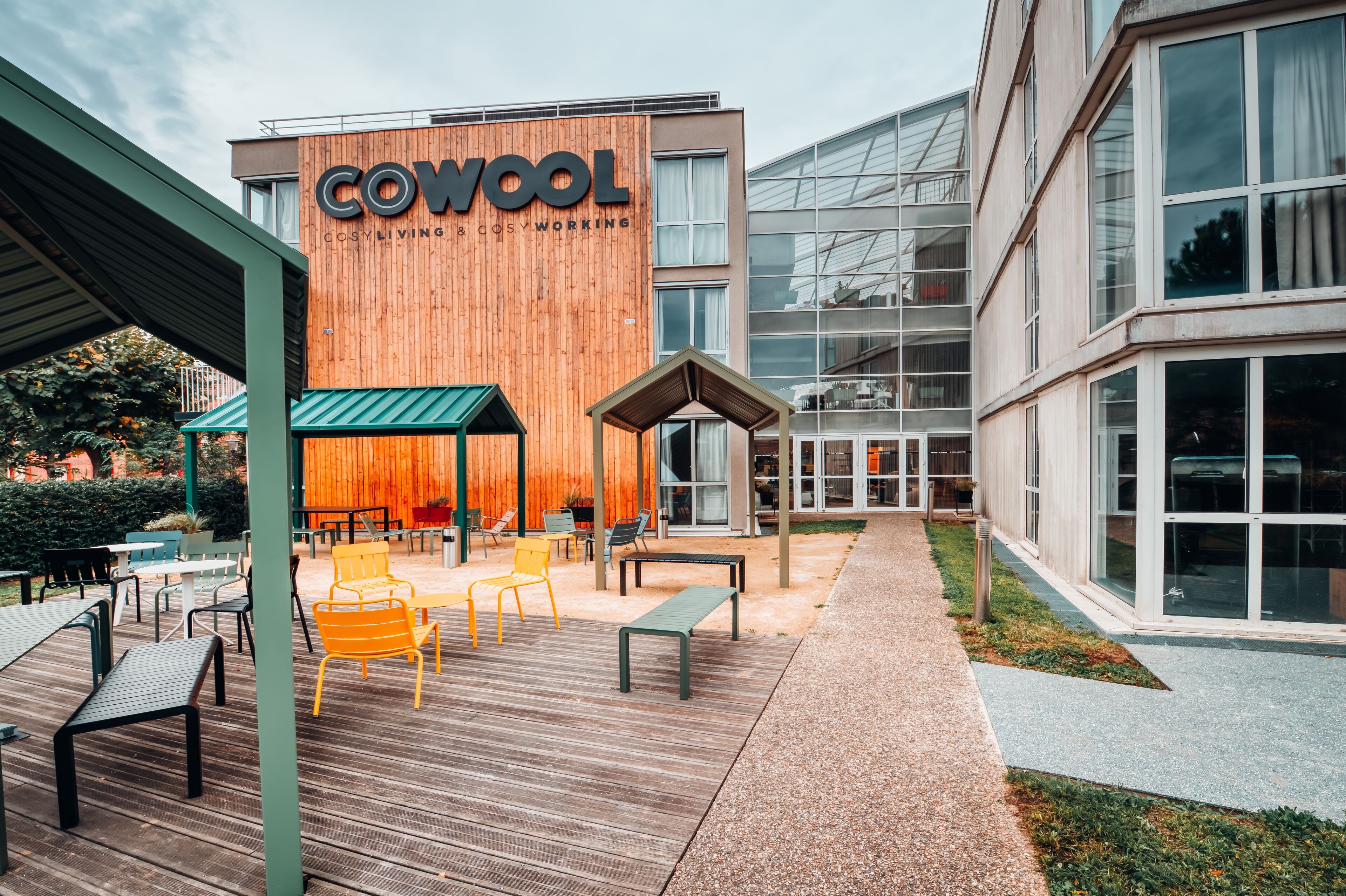 Um edifício moderno com uma placa que diz "COWOOL COSY LIVING & COSY WORKING".