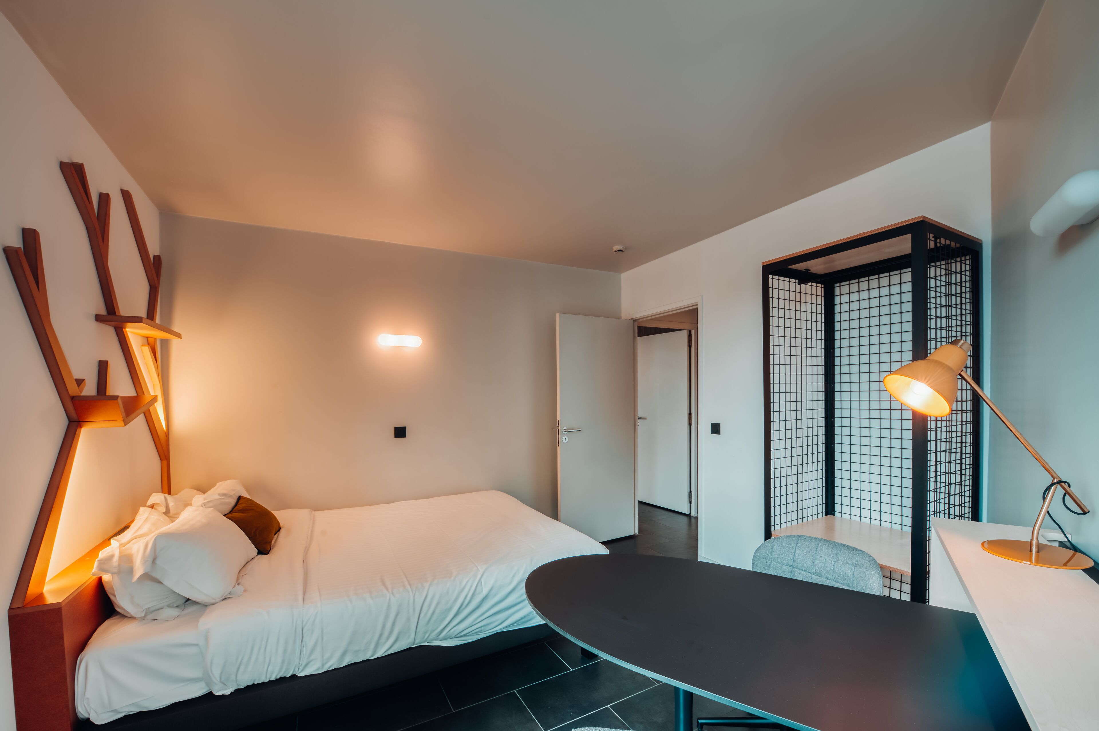 Ein modernes Schlafzimmer mit einem Bett, einem Nachttisch und einem Schreibtisch mit Lampe.