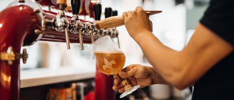 A person pouring a drink from a tap into a glass.