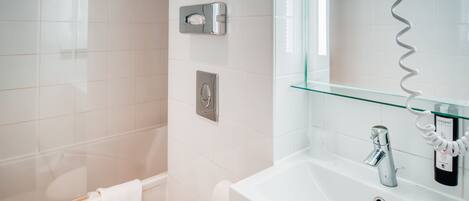 A modern bathroom with a white toilet, a glass shower enclosure, a white sink with a mirror, and a towel rack.