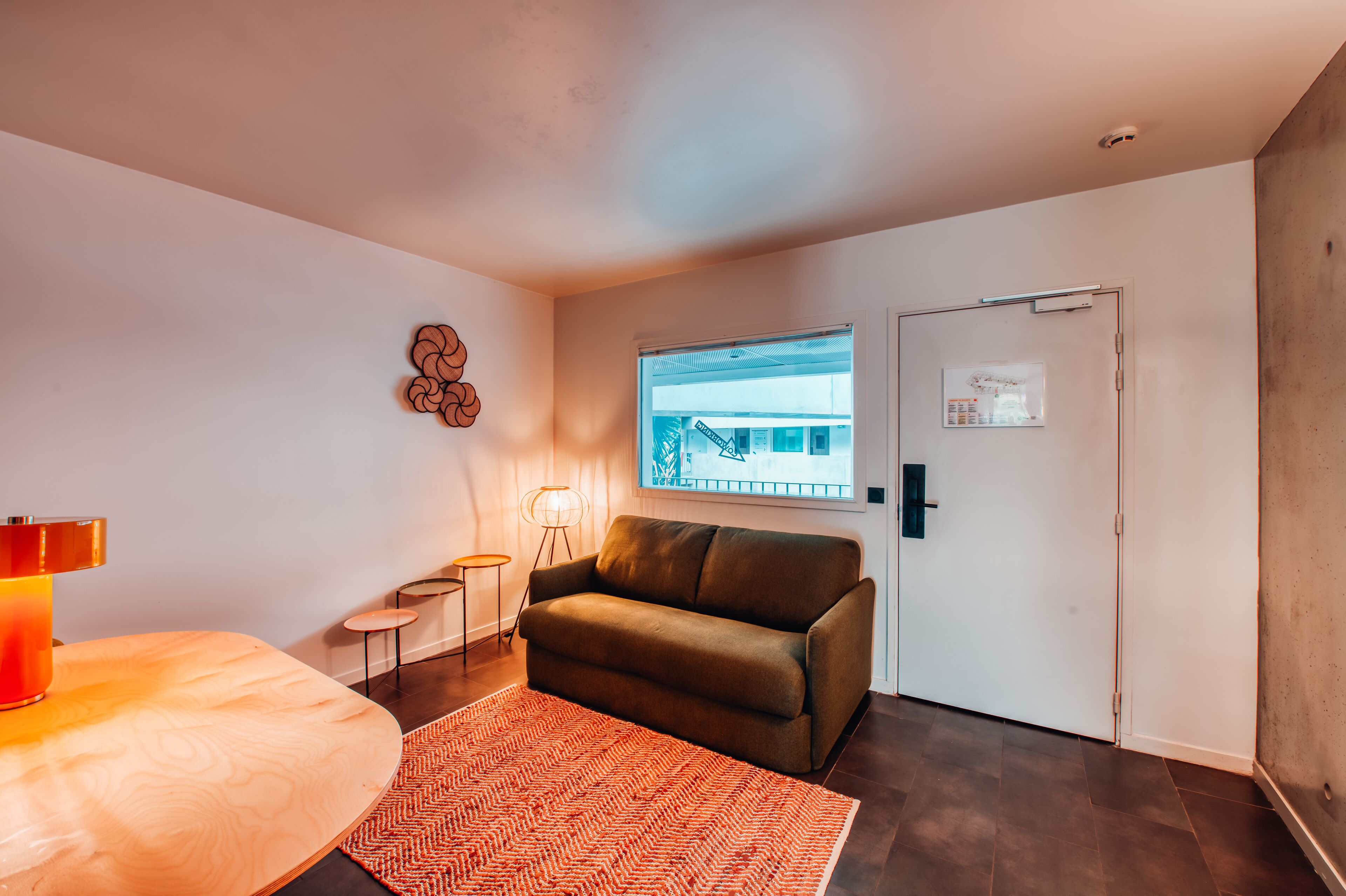 A modern room with a sofa, a small table, a lamp, and a window with a view.