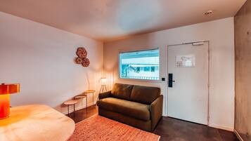 A modern room with a sofa, a small table, a lamp, and a window with a view.