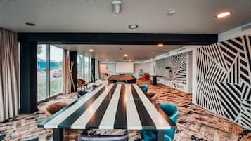 A modern conference room with a long table, comfortable seating, and a large window offering a view of the outside.