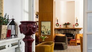 Uma sala de estar espaçosa com lareira, uma área de jantar com mesa e cadeiras, e um corredor que dá para outro quarto.