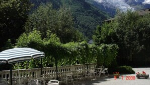 Terraço com área de estar ao ar livre, rodeado por vegetação exuberante e montanhas ao fundo.