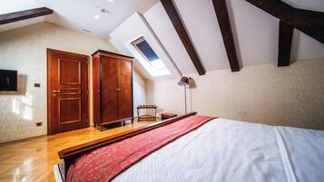A bedroom with a skylight, wooden wardrobe, and a bed with a red bedspread.