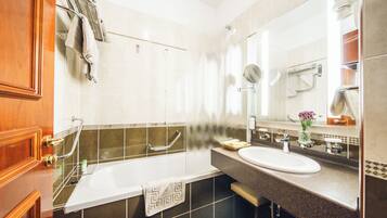 Un baño moderno con bañera, lavamanos y un espejo grande.