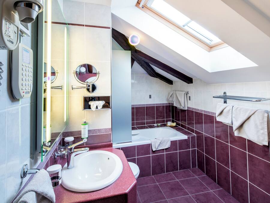 Een moderne badkamer met dakraam, telefoon, wastafel en bad.