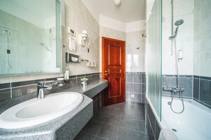 Un baño moderno con lavamanos de granito, cabina de ducha de vidrio y puerta de madera.