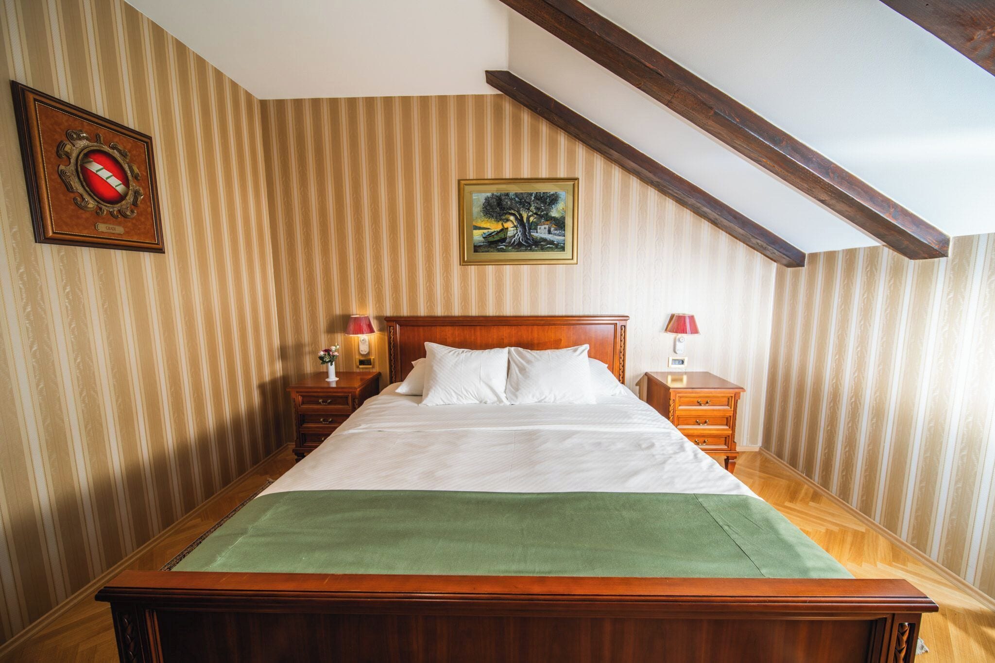 Un dormitorio con cama de madera, papel tapiz a rayas, un cuadro y un reloj en la pared.