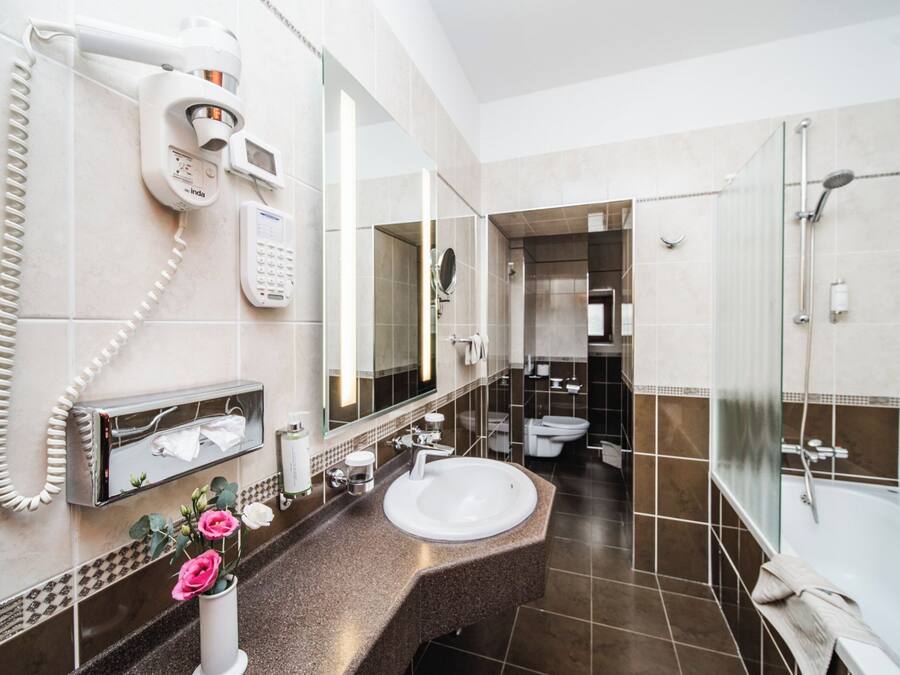 Une salle de bain moderne avec un grand lavabo, une douche en verre et des toilettes visibles au fond.