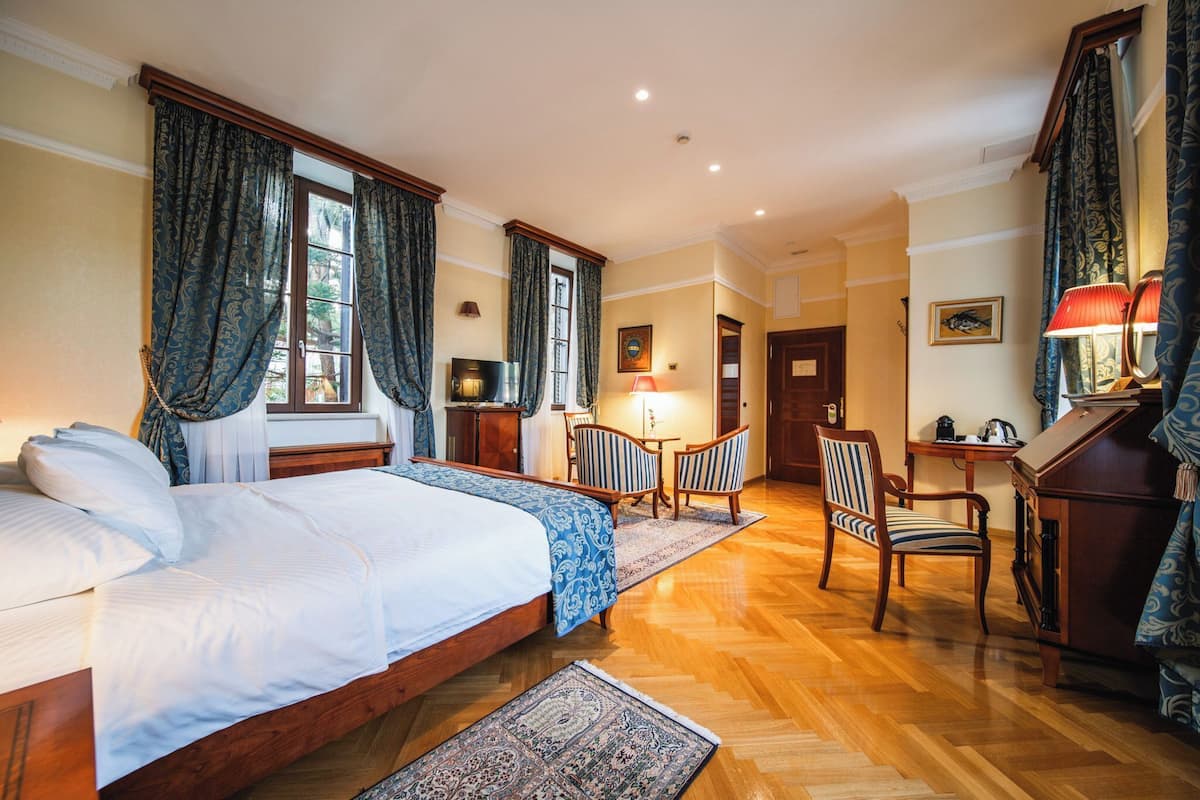 Ein Hotelzimmer mit einem großen Bett, zwei Stühlen, einem Schreibtisch und einer Lampe.