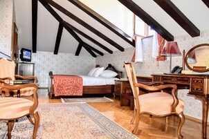 Quarto com cama de madeira, escrivaninha, cadeira, tapete e televisão.