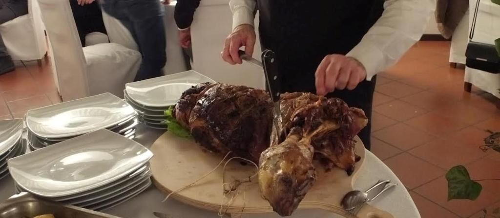 Une personne est en train de découper une grande pièce de viande rôtie sur une planche à découper en bois.