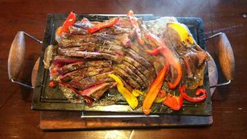 A grill with sliced meat and vegetables on a wooden table.