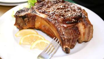 A steak with lemon slices on a white plate.