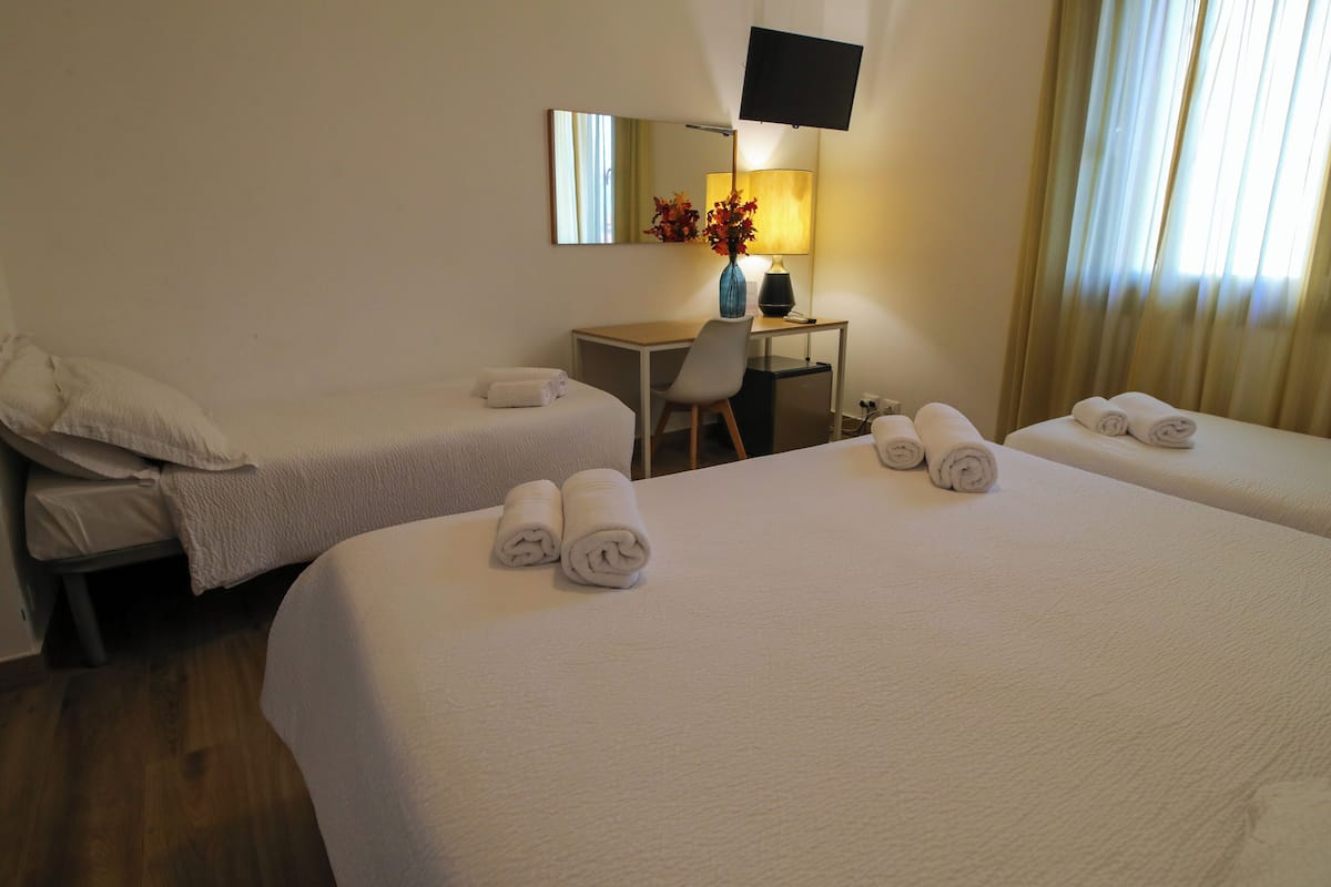 Een hotelkamer met twee bedden, een bureau, een stoel, een televisie en een lamp.