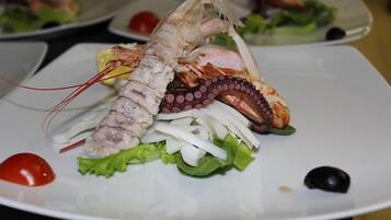 Un piatto con astice, polpo e verdure.
