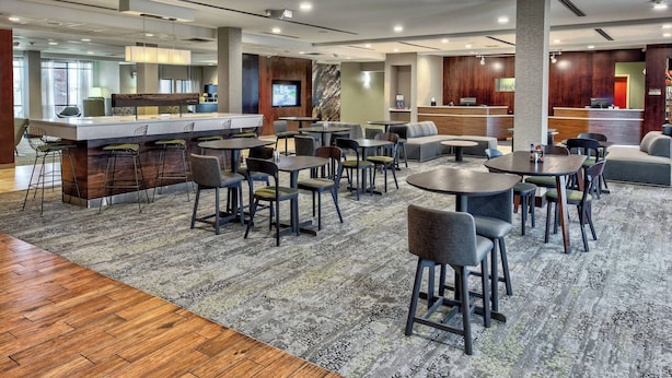 A modern hotel lobby with a bar area, seating arrangements, and a reception desk. - Courtyard by Marriott Lima (Lima)