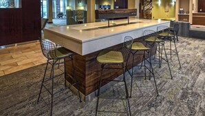 A bar area with a long counter and four bar stools. - Courtyard by Marriott Lima (Lima)