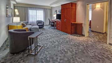 Habitación de hotel con sofá, sillón, escritorio y armario.