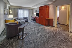 Habitación de hotel con sofá, sillón, escritorio y armario.