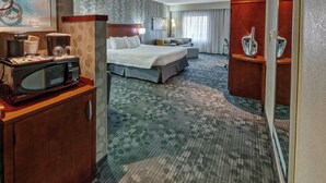 A hotel room with a bed, a desk with a microwave, a sofa, and a cabinet. - Courtyard by Marriott Lima (Lima)