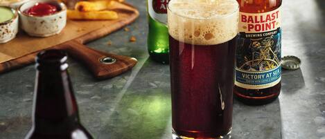 Una jarra de cerveza, una botella de cerveza Ballast Point y una botella de cerveza Liguus sobre una mesa.