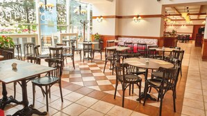 Un restaurante espacioso con techos altos, pisos de baldosas de cuadros y diversas opciones de asientos, como mesas y cabinas.