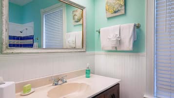 A bathroom with a sink, mirror, and two towels on the wall.
