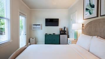 A bedroom with a bed, a television, a microwave, a teal dresser, and a ceiling fan.