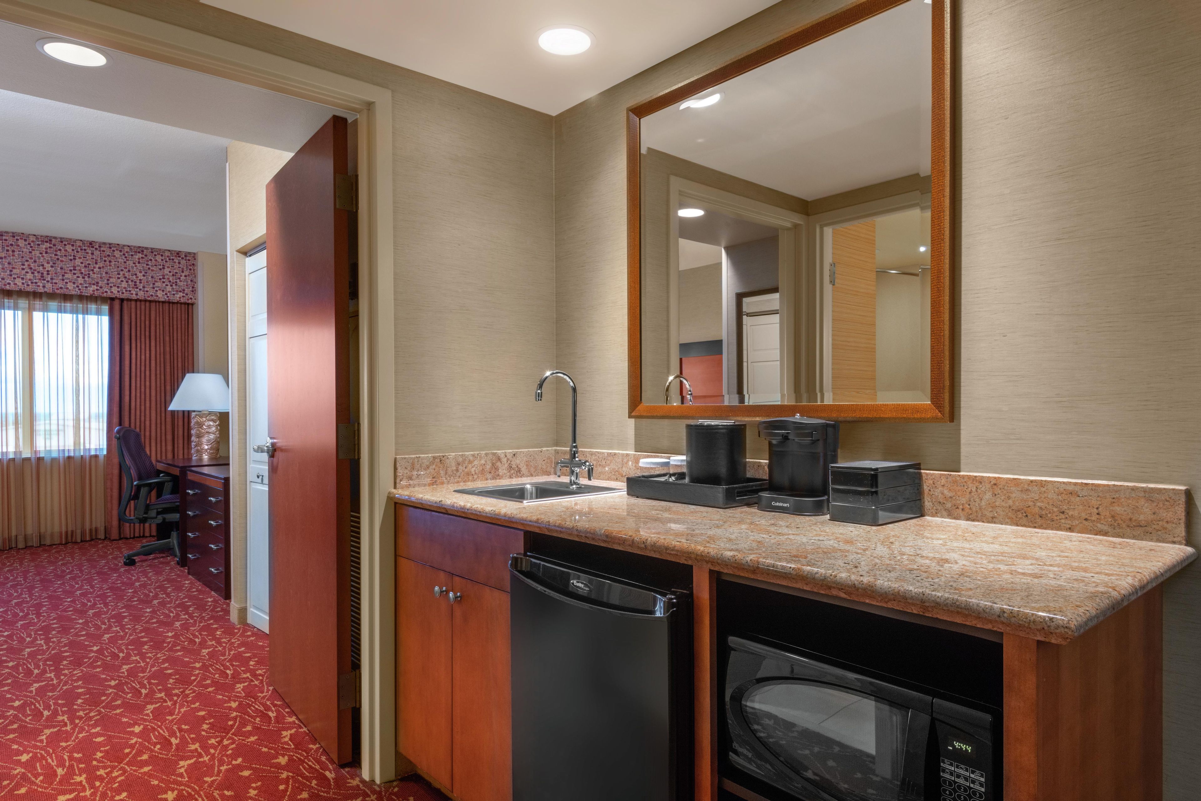 A hotel room with a kitchenette, including a sink, coffee maker, and microwave.