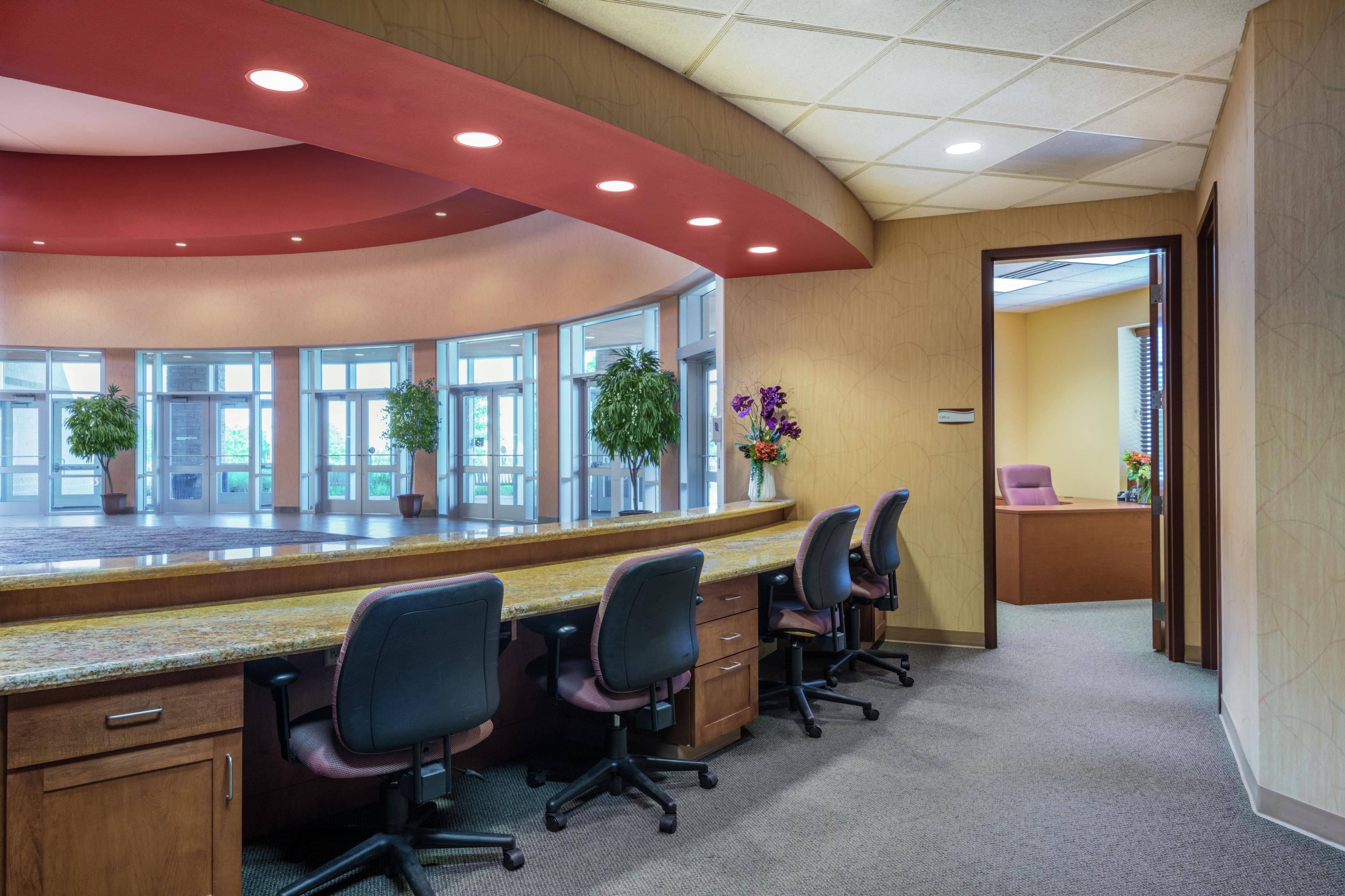 A conference room with a curved desk, multiple chairs, and potted plants.