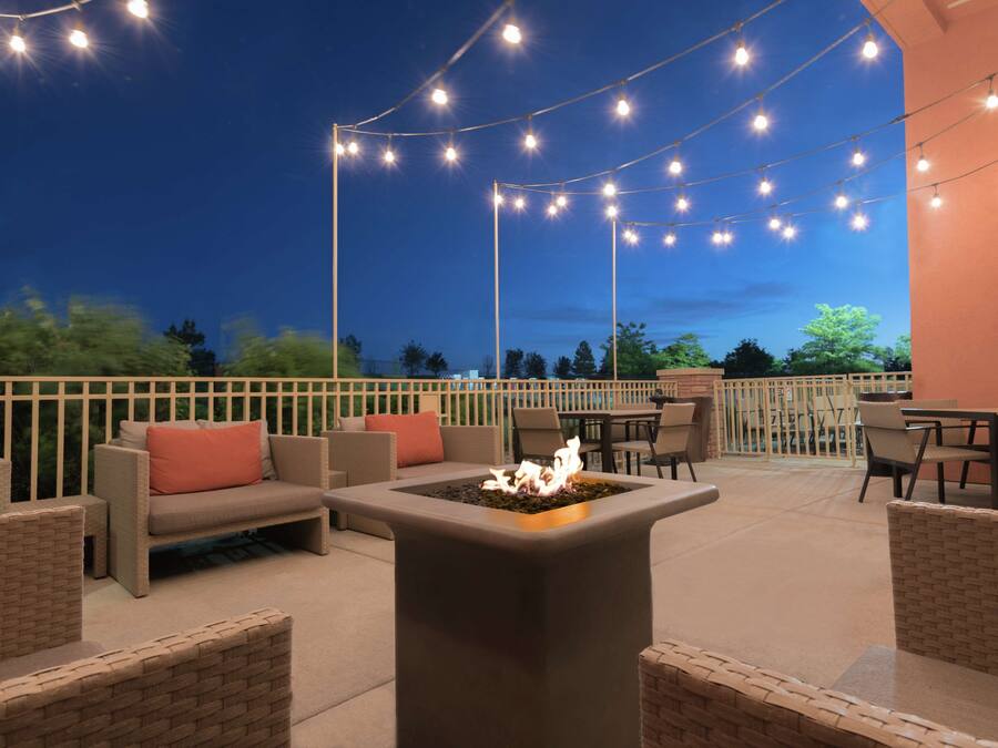 An outdoor patio area with a fire pit, string lights, and outdoor furniture.