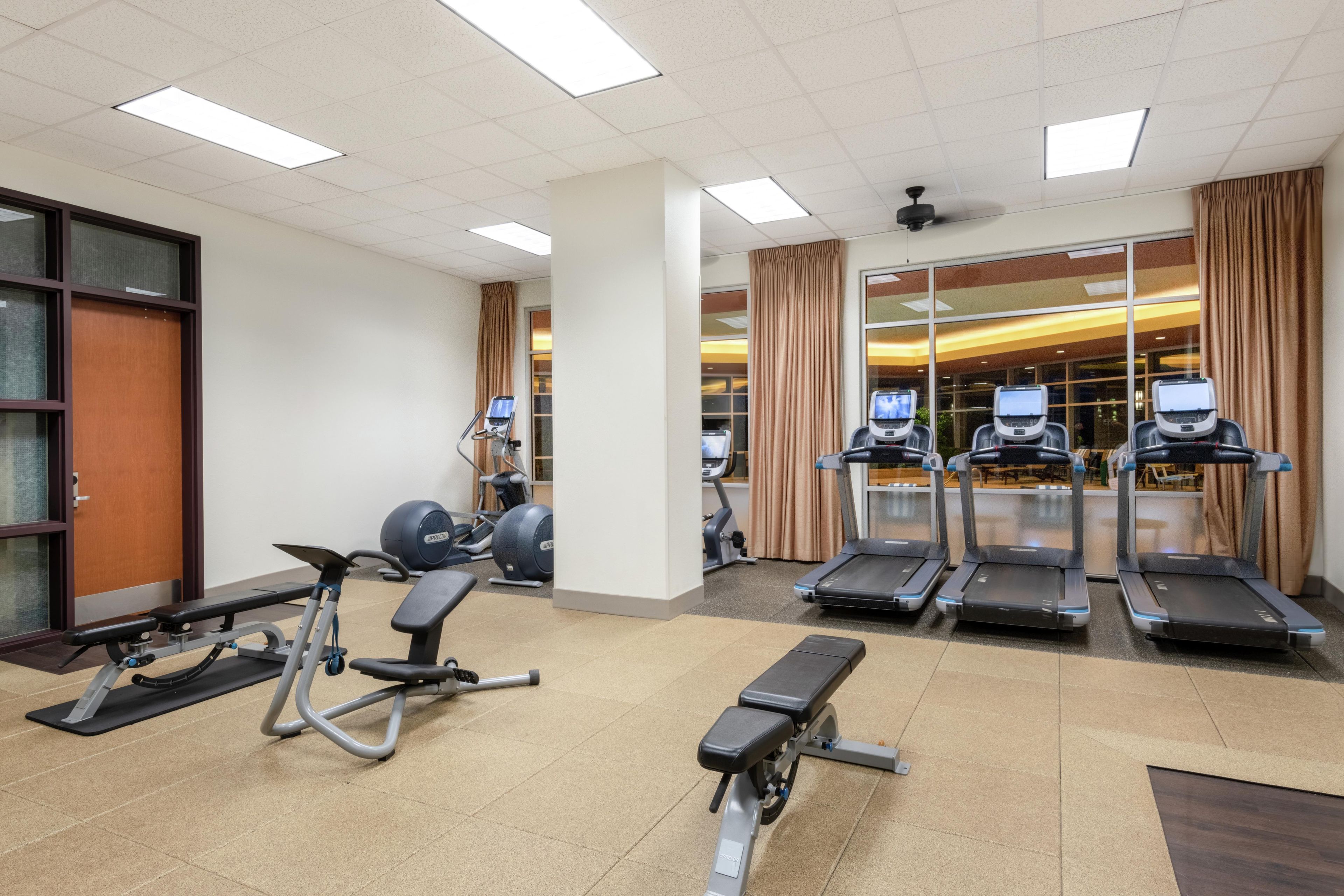 Un gimnasio con cintas de correr, bicicletas estáticas y máquinas de pesas.