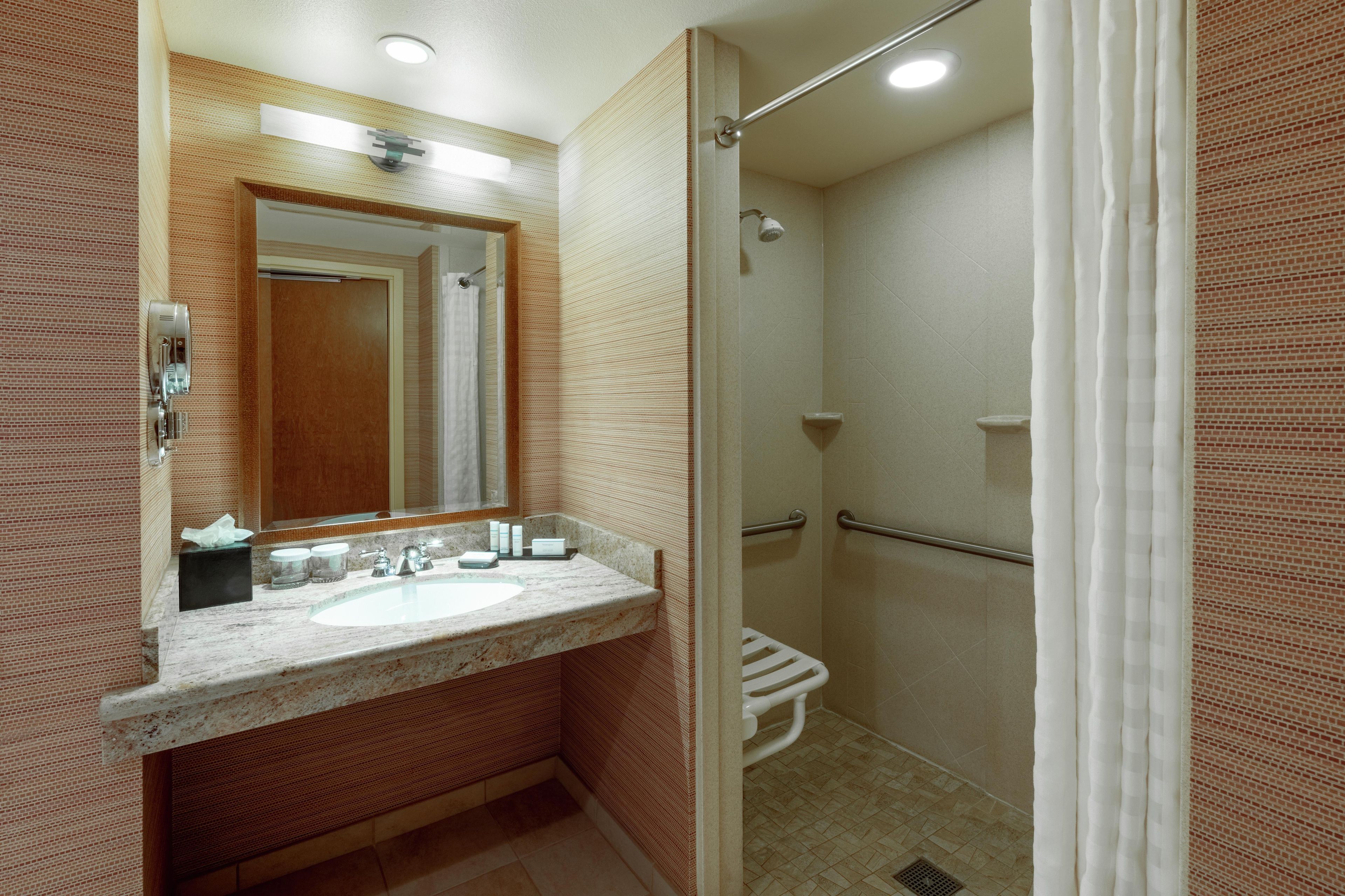A bathroom with a sink, mirror, shower, and toilet.